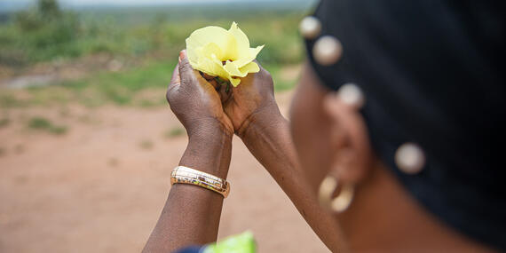 A female survivor of sexual violence holds a flower to her face,