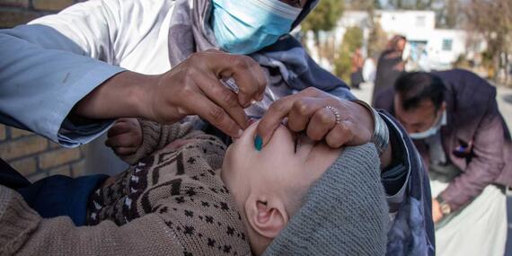 An aid worker vaccinates a child against polio.