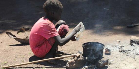 A child cooking on a makeshift stove 