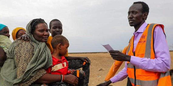 A UNHCR staff member with women and children, arriving in Renk, South Sudan.