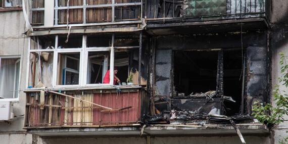 A woman tries to clean her apartment of debris following a Russian rocket explosion