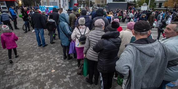 People queue to receive humanitarian aid in the central square of Kherson