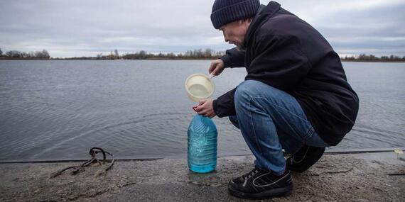 A man fills his bottle with water from the Dnipro River.