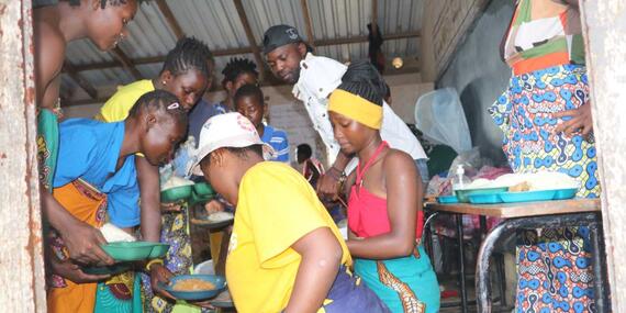 Volunteers help serve food at the Manja displacement site.