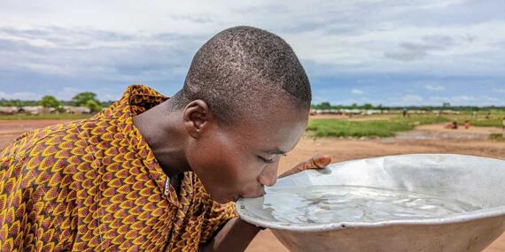 A man takes a sip of fresh water from a well 