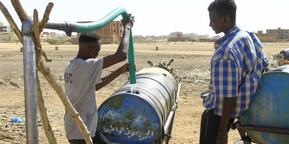 People fill barrels of water in southern Khartoum on 22 April, 2023, amid water shortages caused by the ongoing fighting. 