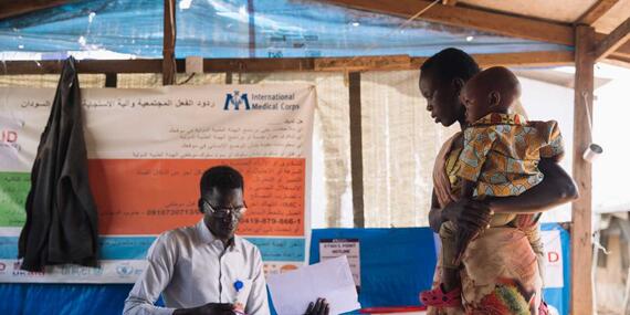 A healthcare worker registers a woman and her sick son at a clinic in Malakal at a site for people displaced by violence in South Sudan.