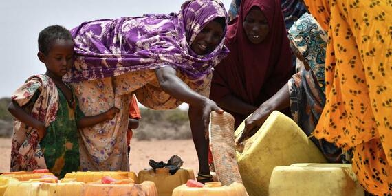 A group of women fetch water at a water trucking point