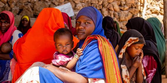 A woman holds her small child in a Somali health clinic