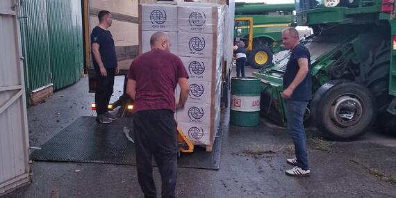 Men unload boxes with the UN IOM logo on them from a truck.
