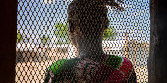 A women looks out of a window with a mesh.