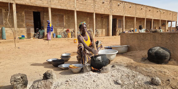 A displaced woman prepares millet in a school’s courtyard where she and her family have taken shelter. Burkina Faso.