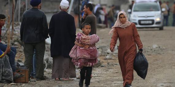 A woman and child carry possessions through the streets of Rafah.