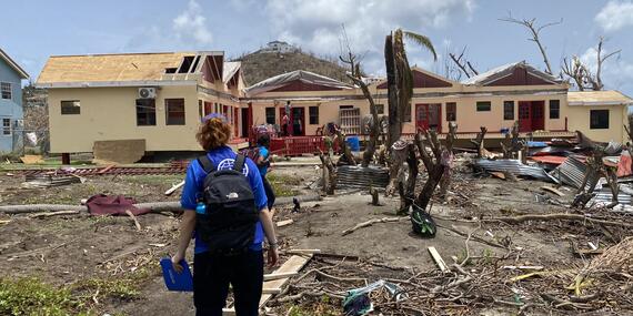 A building sustained significant damage, with debris scattered around and parts of the roof missing following Hurricane Beryl.