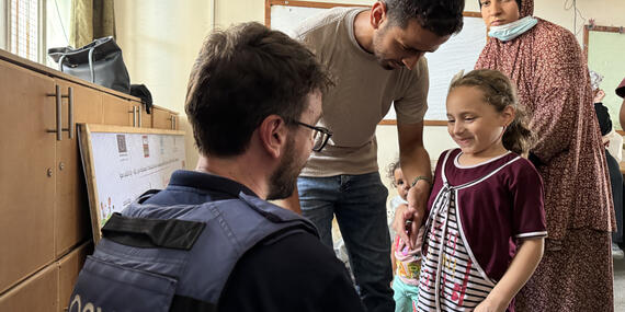 A member of the UN Office for the Coordination of Humanitarian Affairs (OCHA) interacts with a young girl at a school in Gaza