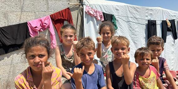 Children in Gaza proudly display their marked pinky fingers after receiving polio vaccinations as part of a successful campaign that immunized over 187,000 children, surpassing the target of 156,500.