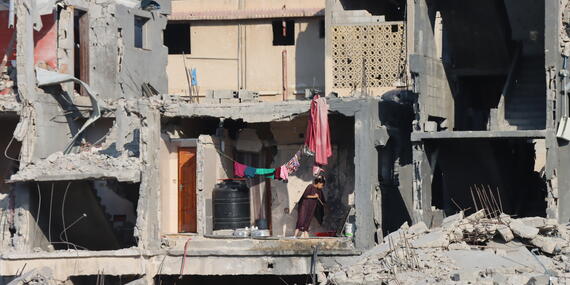 A Palestinian girl cleans the floor of a heavily damaged house in Abasan Al Kabira, area of Khan Younis. 