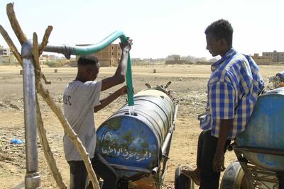 People fill barrels of water in southern Khartoum on 22 April, 2023, amid water shortages caused by the ongoing fighting. 