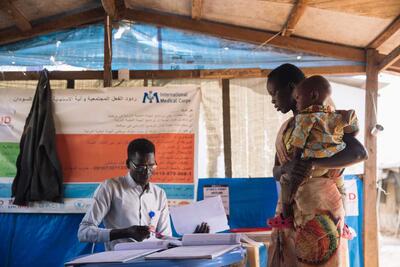 A healthcare worker registers a woman and her sick son at a clinic in Malakal at a site for people displaced by violence in South Sudan.