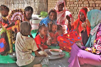 Khadidja (in red) shares a meal with her family and Sudanese refugees.