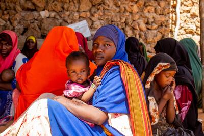 A woman holds her small child in a Somali health clinic