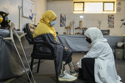 Girl in Afghanistan with prosthetic leg being fitted by doctor.