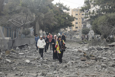 People walk through rubble 