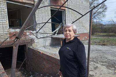 Nadiia stands next to the damaged sports complex, which had become a collective centre for internally displaced people in Dnipro, Ukraine