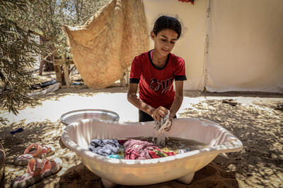 A displaced girl washing clothes in a refugee camp in Khan Younis. Gaza.