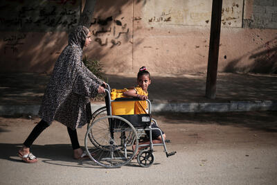 Palestinian girls use a wheelchair to carry water in Khan Younis city, in the southern Gaza Strip.