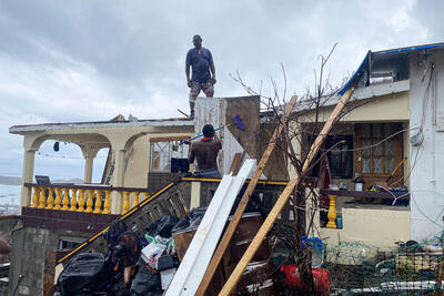 Men in Grenada try to fix a roof in the aftermath of Hurricane Beryl. The hurricane caused severe damage to infrastructure, services and livelihoods in Grenada, Saint Vincent and the Grenadines, and Jamaica.