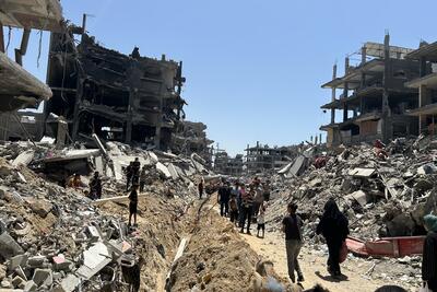 Residents walk through the rubble and destruction in Gaza, surveying the aftermath of recent conflict.