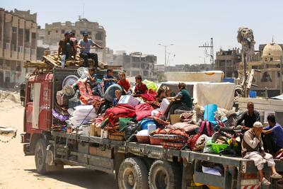 Displaced families in Gaza load their belongings onto a truck as they flee their homes due to ongoing conflict and destruction in the region.