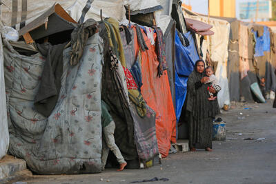 A woman and her child stand outside a makeshift shelter in Gaza, where the ongoing conflict has led to the displacement of thousands