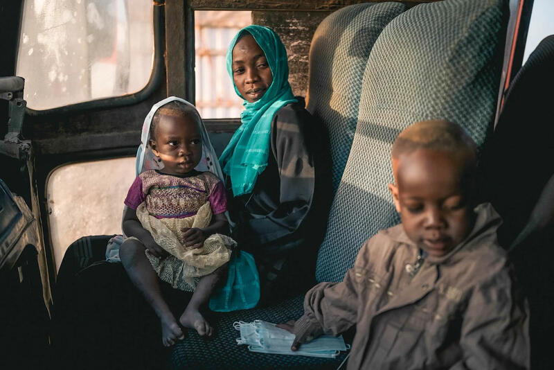 A mother and her children sit inside a vehicle after fleeing the war in Sudan.