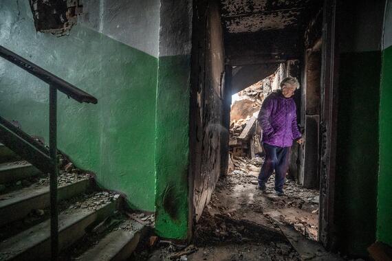 A lady looks onto the ruins of her apartment