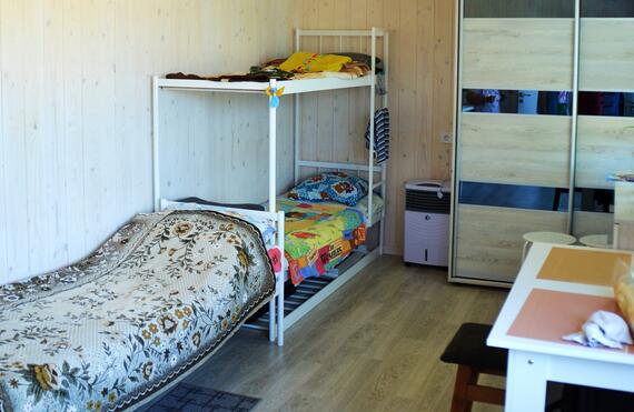 Inside of a romm with two bunk beds and a single bed with some drawers against the wall