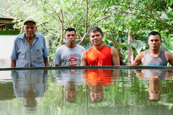 Four men stand behind a water filled tank.
