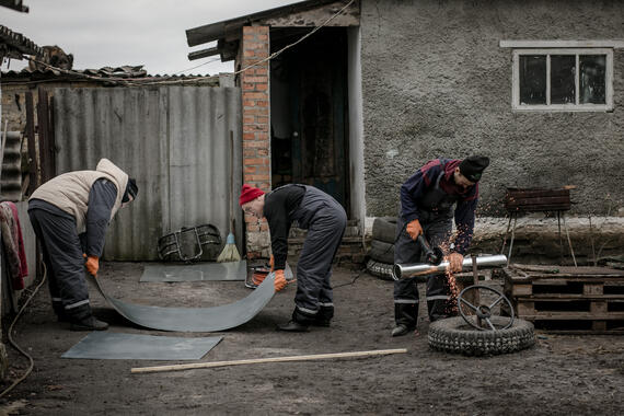 Men work outside in a yard on pipes and with cement,