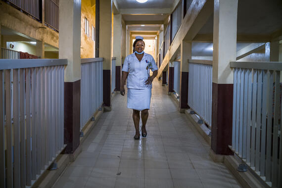 A woman in a nurse's unform is walking down a corridor.