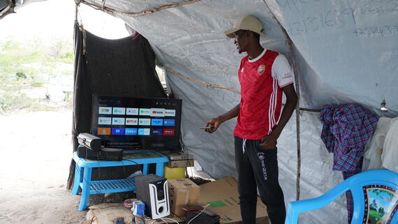 Jason shows his selection of entertainment at the video café in a tent at Dumi A displacement site