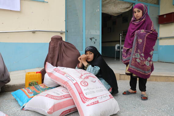 An 11-year-old girl sits beside her family’s food rations at a WFP distribution point in Kandahar Province, Afghanistan