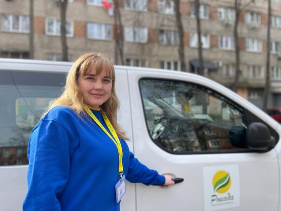 Lyudmyla stands next to a car. She works at the NGO, Rokada in Ukraine’s Sumy Region.