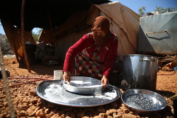 A woman washes dishes in the Al-Hamra camp in Syria's Idleb governorate. 