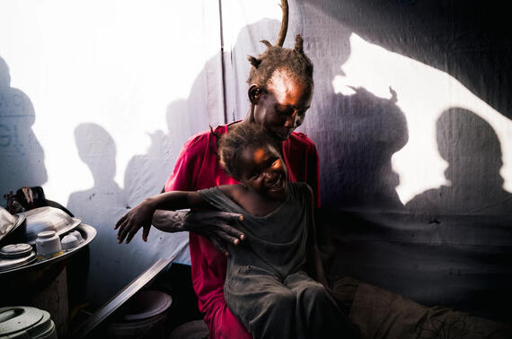 A mother holds her smiling child at the Renk Transit Centre in South Sudan.