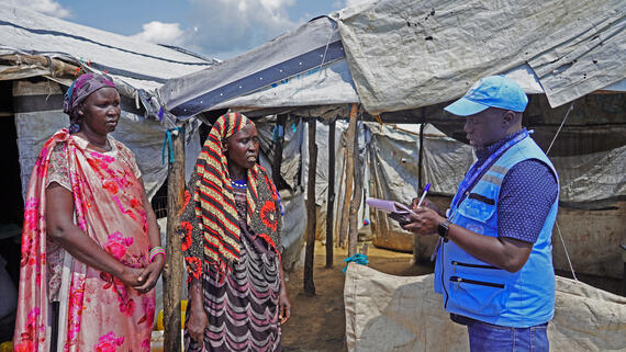 OCHA Humanitarian Affairs Officer Richard Luguma talks with women in the displacement site.