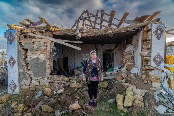 A woman stands in front of her destroyed home in Mykolaiv, Ukraine