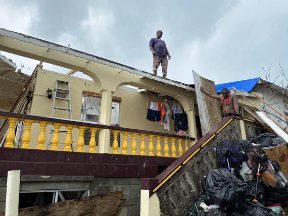 a builder who has lived in his home for more than 40 years, applies temporary sheets to his roof. Hurricane Beryl